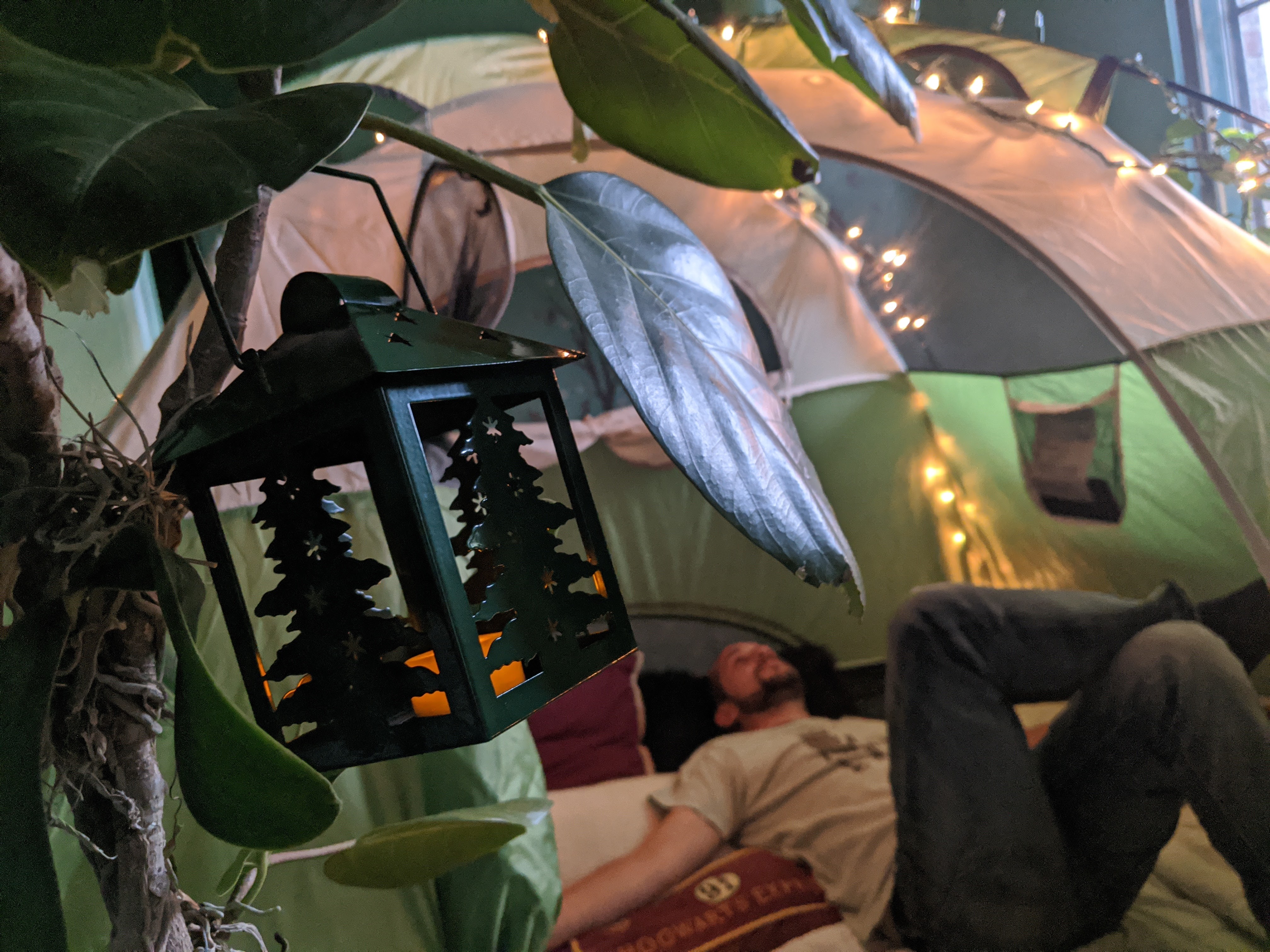 A green tent sits inside the dining room, decorated with twinkle lights and filled with blankets and pillows