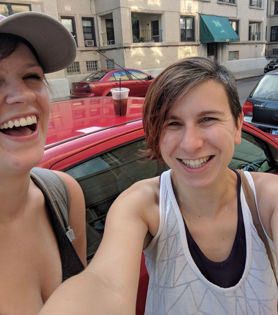 Amanda and Mel, dressed for a summer hike, laugh toward the camera